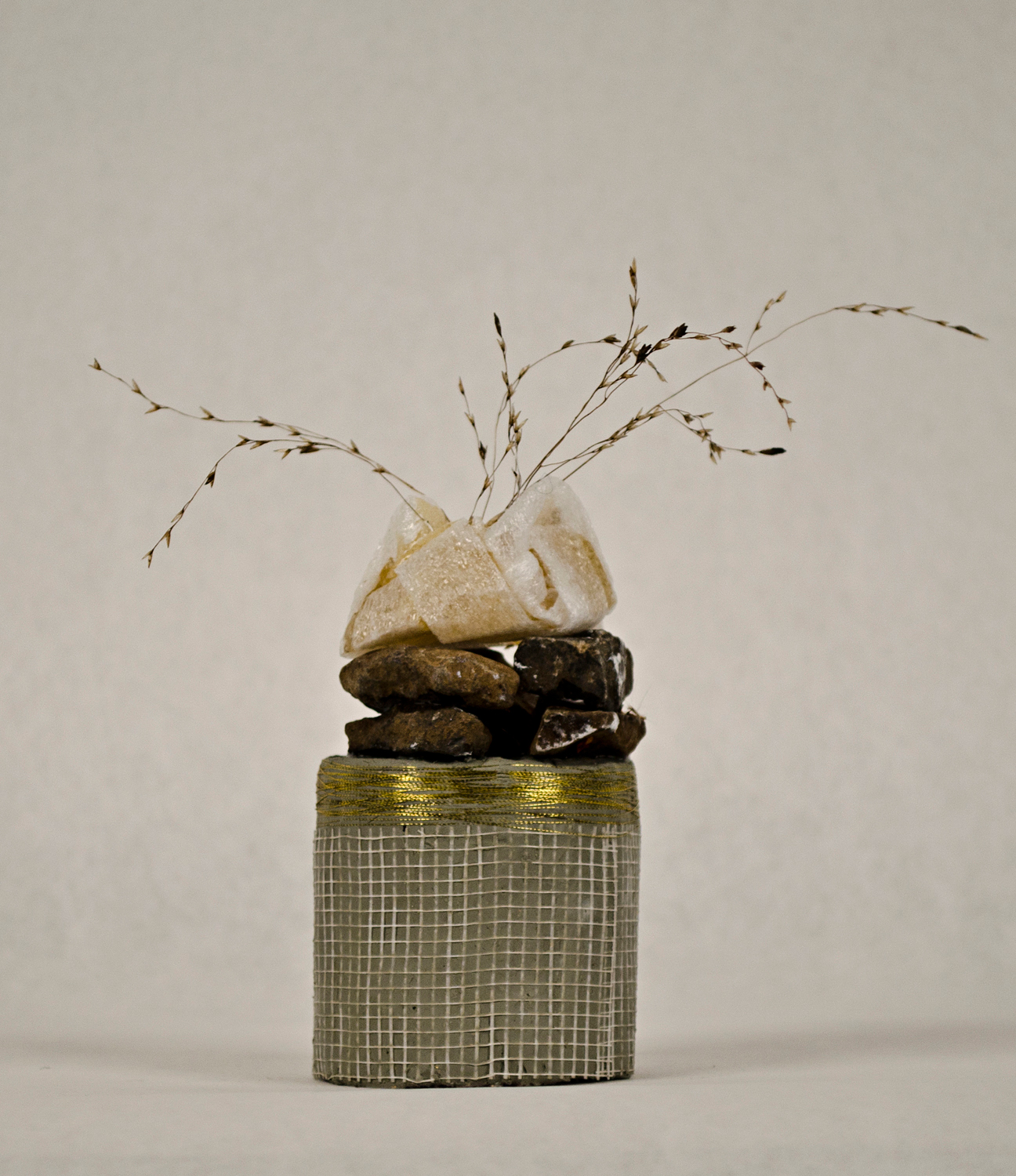 Jessica Lund, feathered, 2014. Clay, drywall tape, gravel, goam, rubber adhesive, grass fronds, 8 x 3 x 3 in.