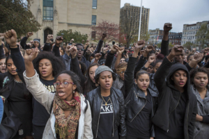 Large group of students of color marching with fists raised