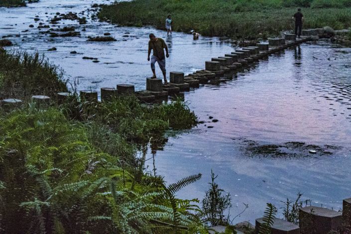 Man walking across a bridge over a river