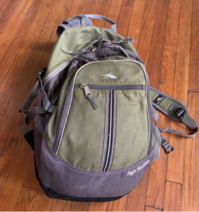 Green backpack on maple colored floor