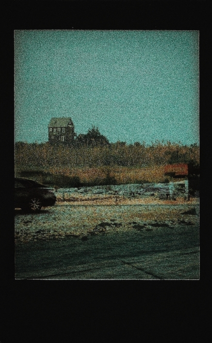 Grainy photograph of a house, car, and field