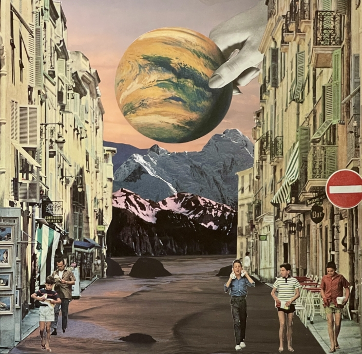 Planet held by a hand over the mountains viewed from a front street where people are walking