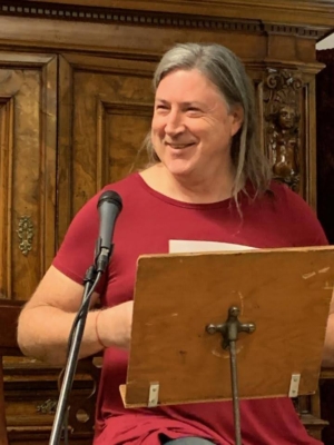 the author, paparouna, at a podium, looking to the side and smiling