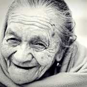 Old woman with a wrinkled face smiling at the camera.