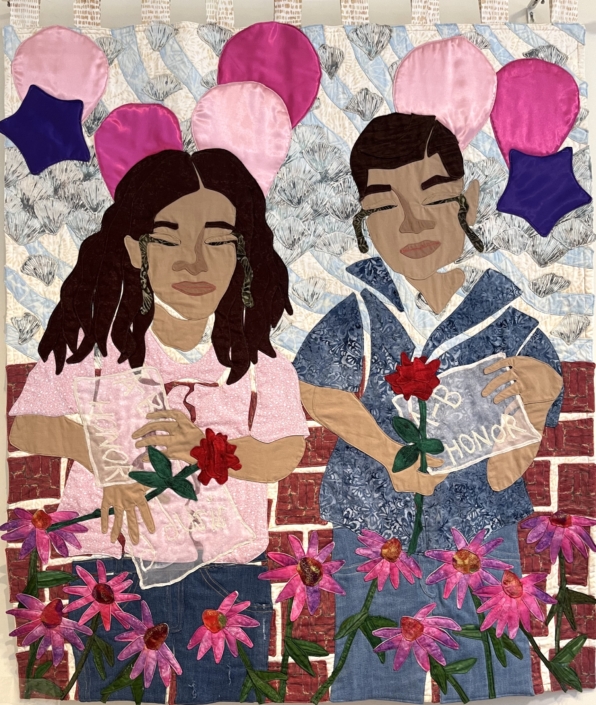 Two people in pink and blue with balloons and a brick wall, pink daisies