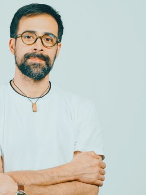 person with glasses looking into the camera with arms crossed