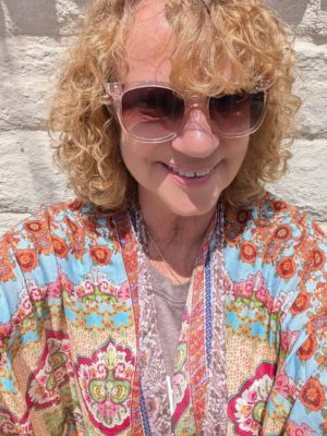 author standing in front a brick wall smiling into the camera