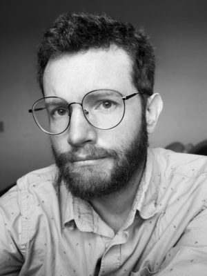 black and white image of the author with glasses looking directly into the camera